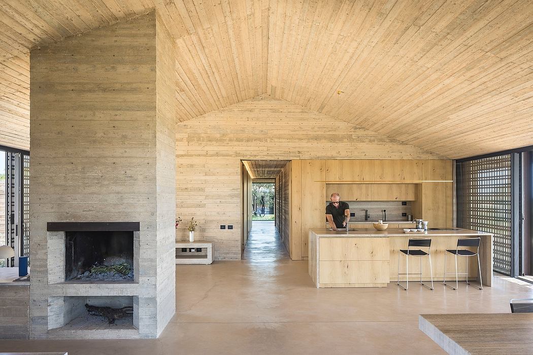 A spacious, rustic wooden interior with a large fireplace and a modern kitchen area.