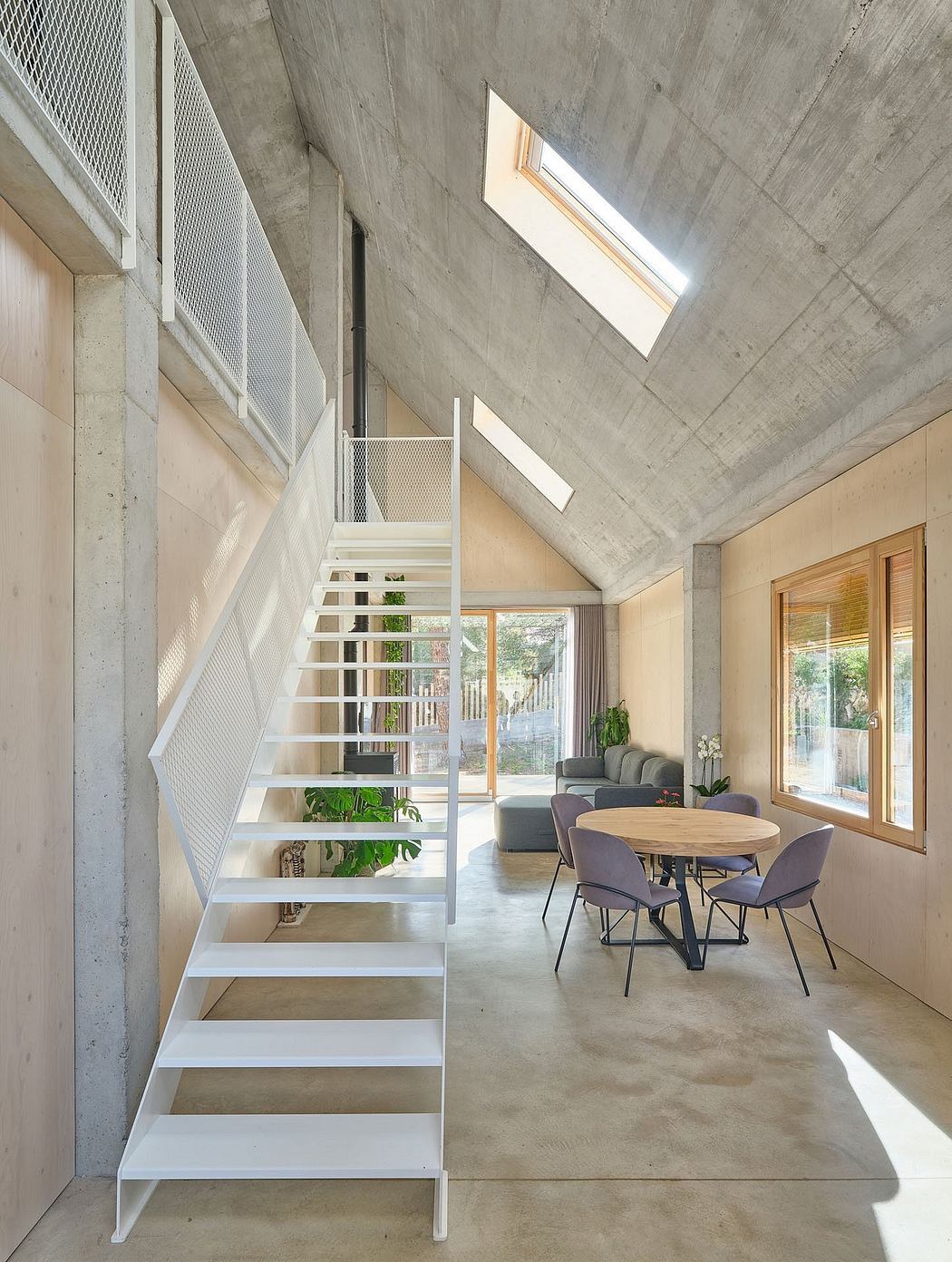 A modern and minimalist open-plan living space with a concrete ceiling, white staircase, and large windows.