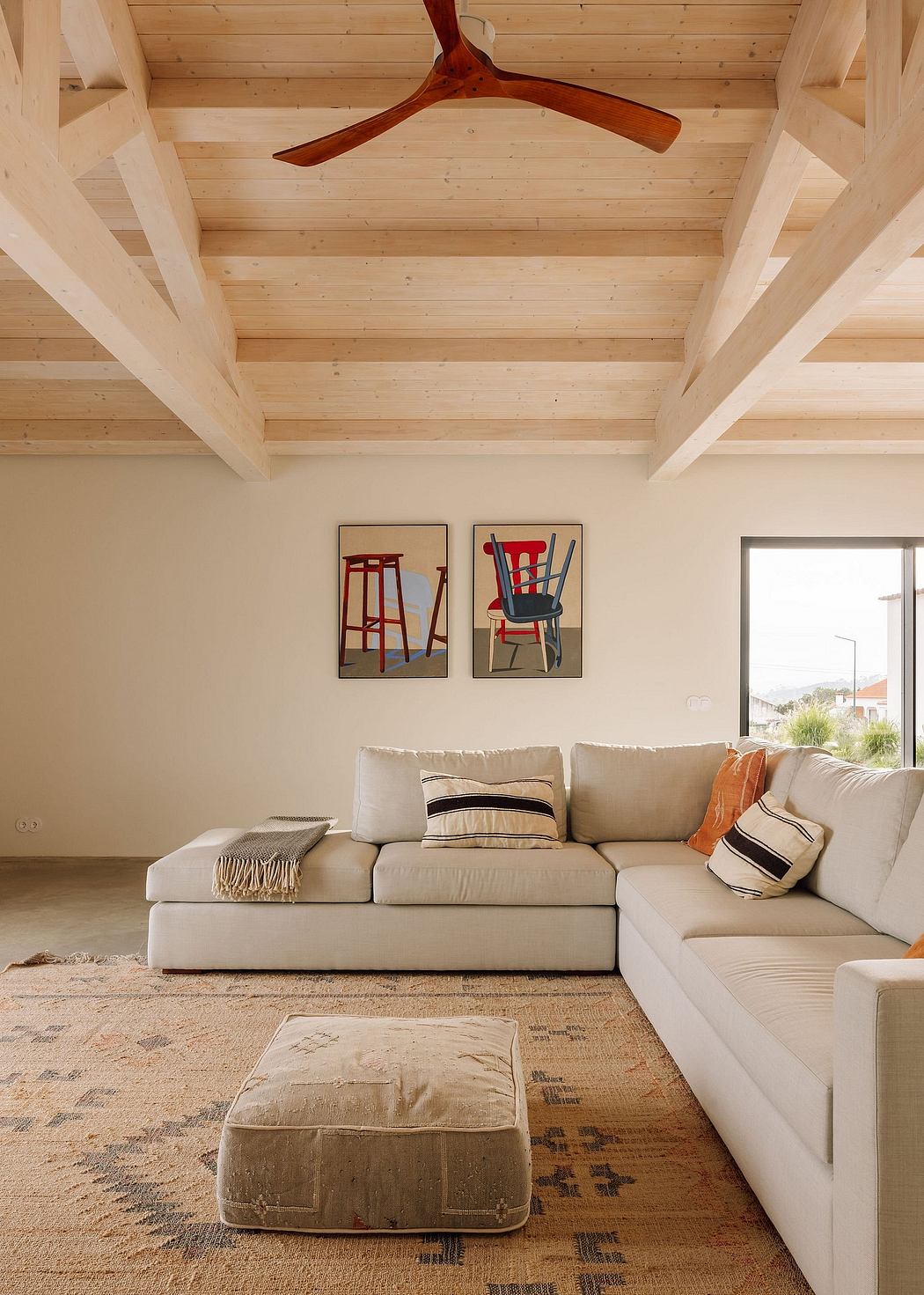 Cozy living room with wooden ceiling, rustic furniture, and abstract wall art.