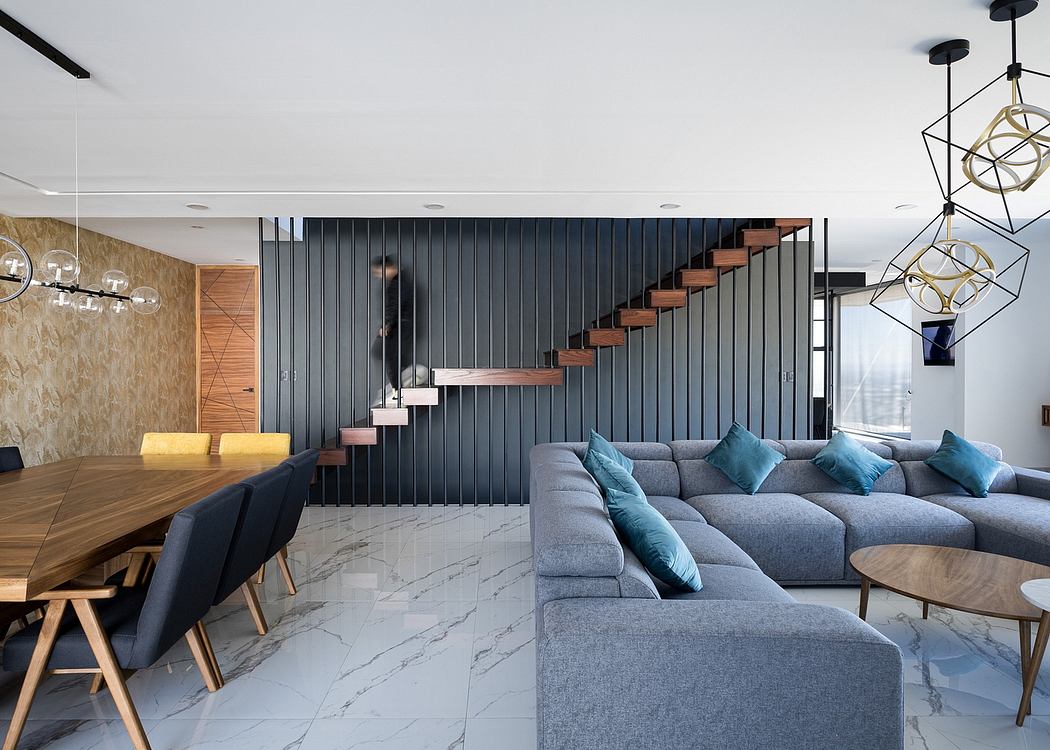 Contemporary open-plan living area with sleek black paneled wall, floating wooden stairs, and cozy grey sectional sofa.