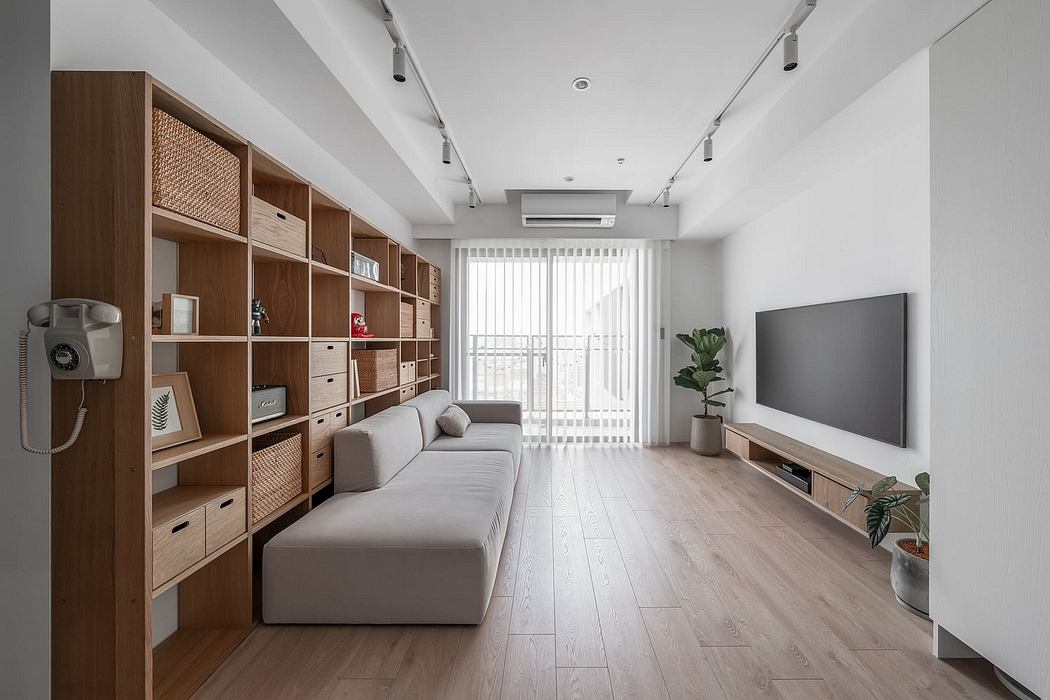 Minimalist living room with wooden storage wall, gray sofa, and large TV unit.