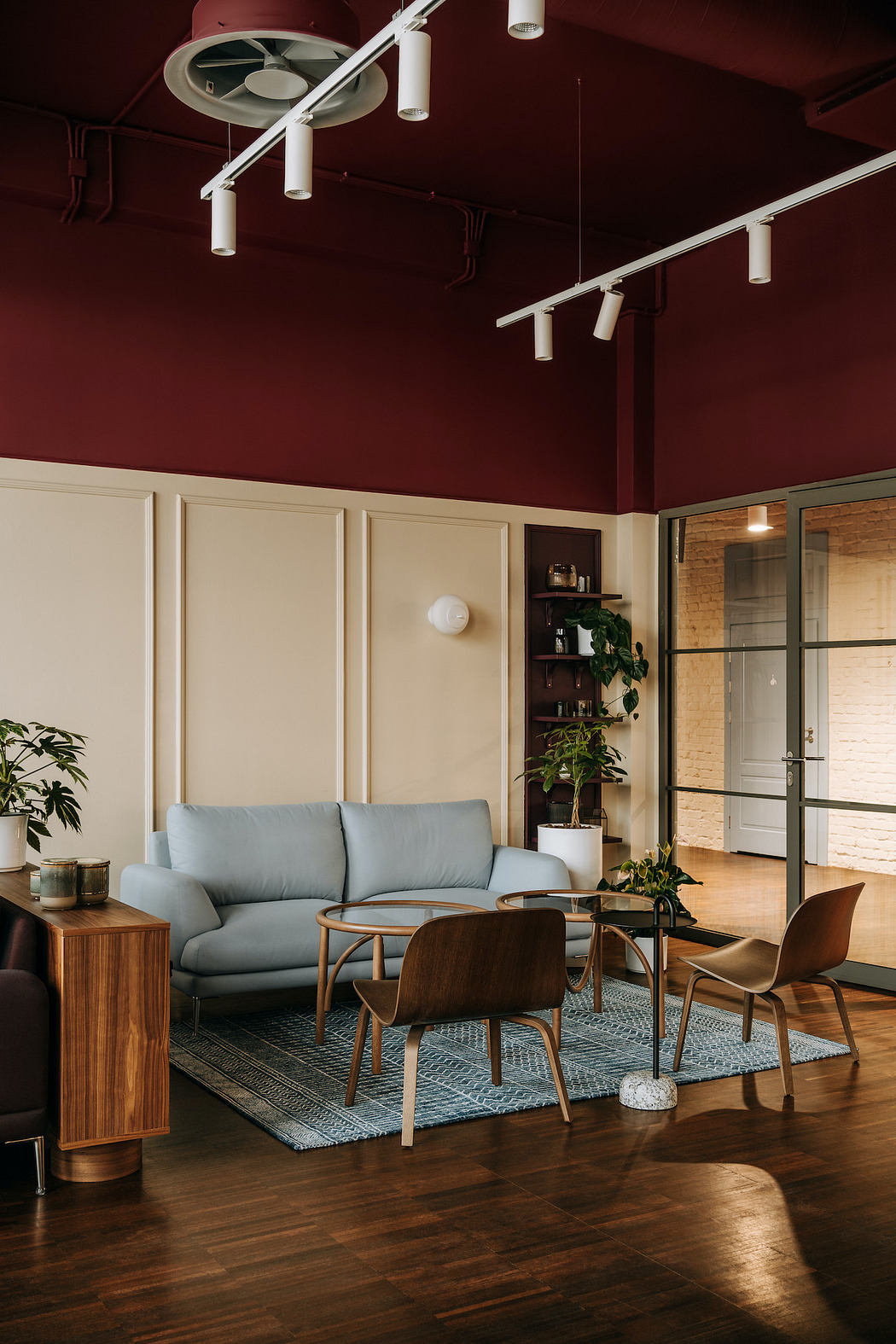 Warm-toned cozy lounge area with plush sofa, wood furniture, and potted plants.