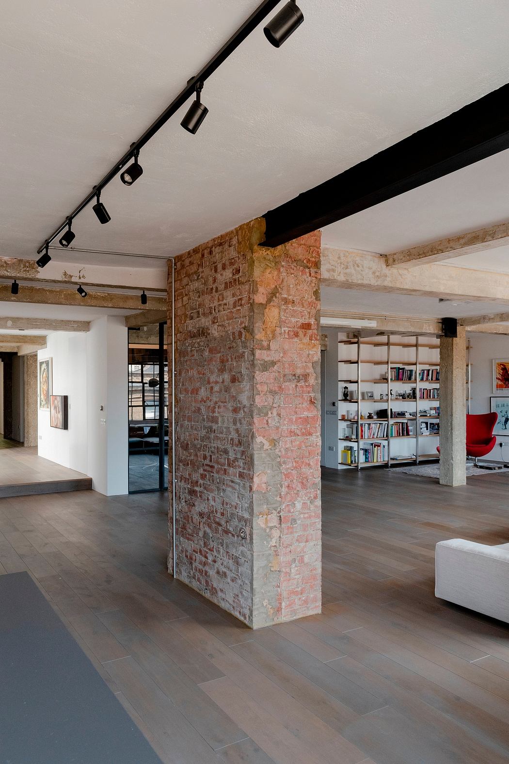 An open-concept loft space featuring exposed brick walls, industrial lighting, and wooden beams.