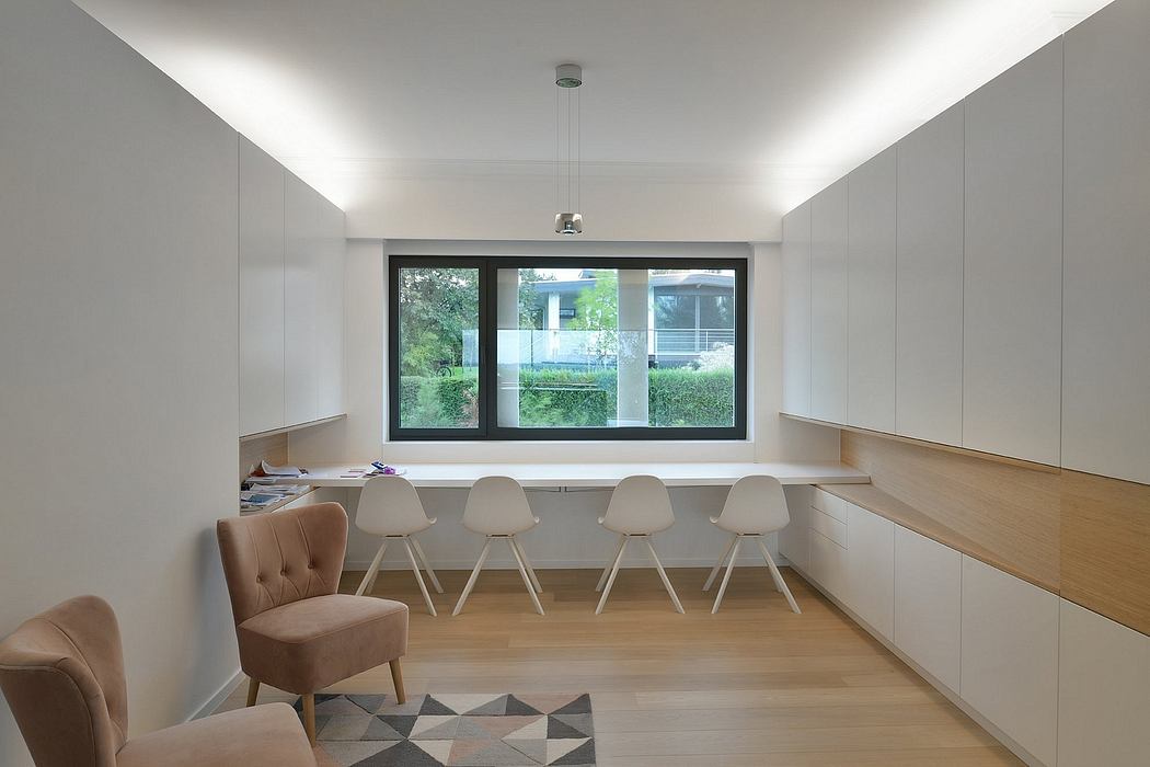 Modern, minimalist room with large window, built-in workspace, and stylish chairs.