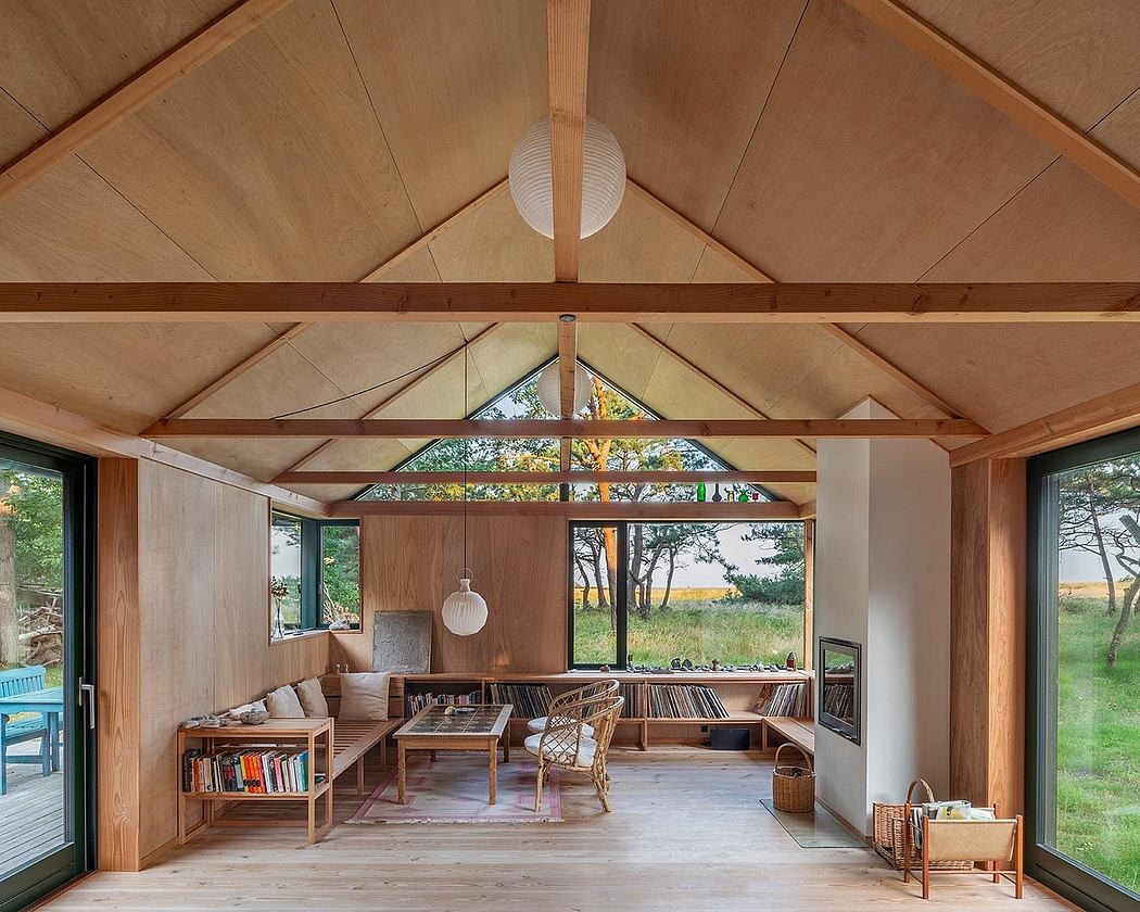 Cozy cabin interior with vaulted wood-paneled ceiling, large windows offering scenic view.