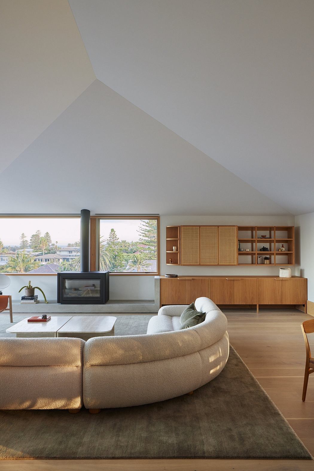 Minimalist living room with wood-paneled cabinetry, cozy sofa, and expansive window views.