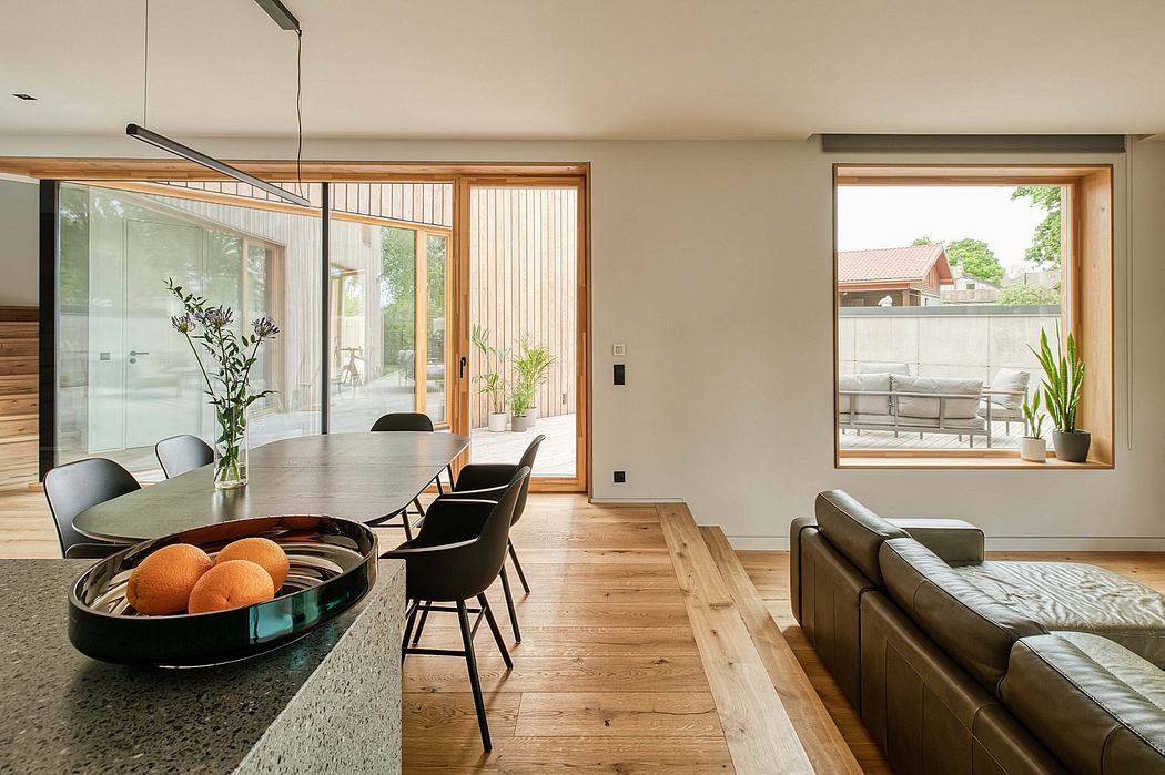 Bright, modern open-plan living space with wooden floors, large windows, and minimalist furnishings.