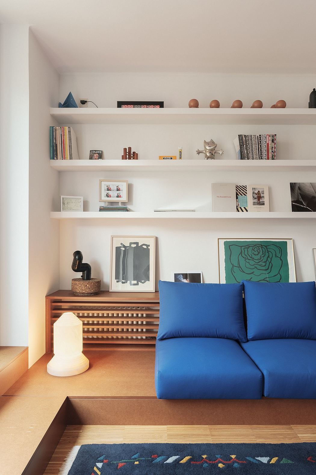 A tastefully designed living space with modern shelves, art, and a cozy blue sofa.