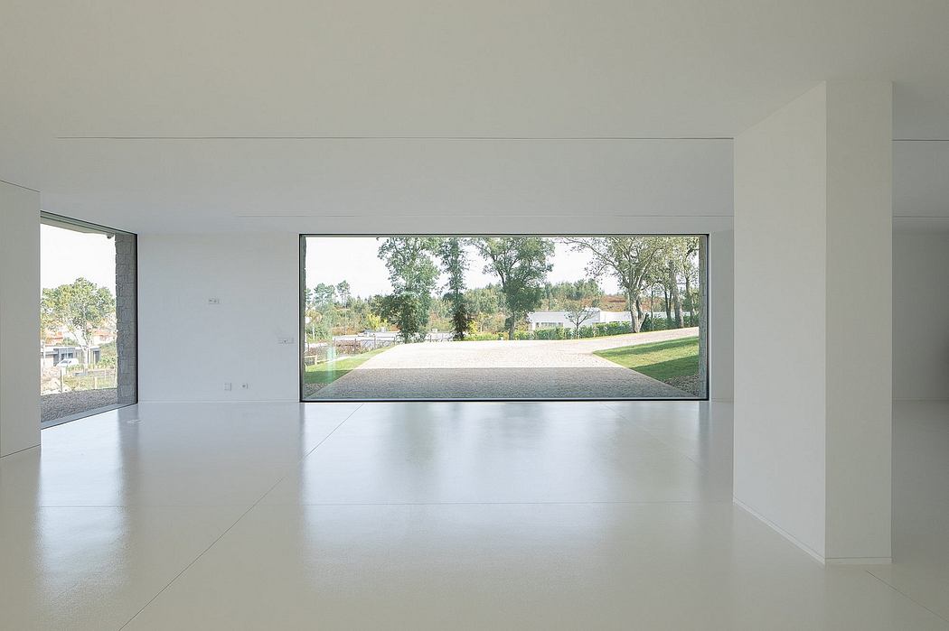 Spacious, minimalist interior with expansive views of lush greenery through floor-to-ceiling windows.