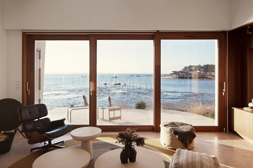 Cozy living space with large windows offering a stunning view of the coastline, featuring minimalist furniture and decor.