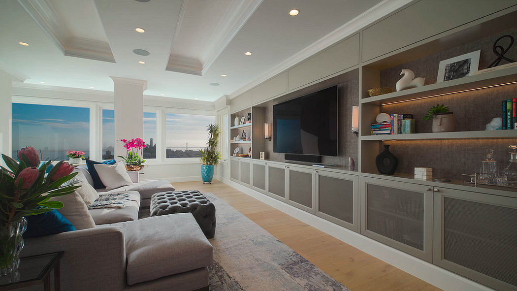Spacious living room with built-in shelving, wall-mounted TV, and panoramic city views.