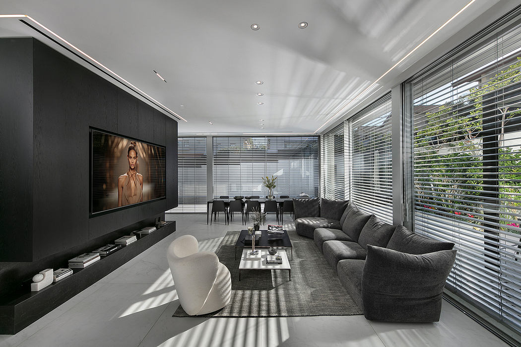 Sleek, modern living room with a large TV, sectional sofa, and floor-to-ceiling windows.