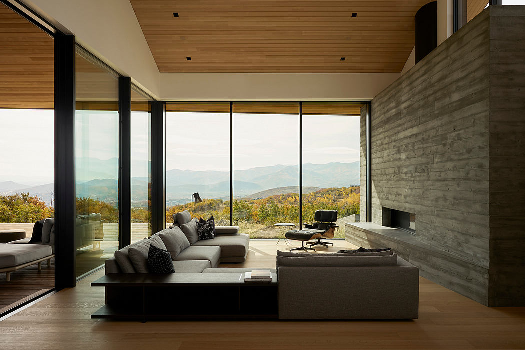 Stunning modern living room with expansive mountain views, sleek furniture, and concrete walls.
