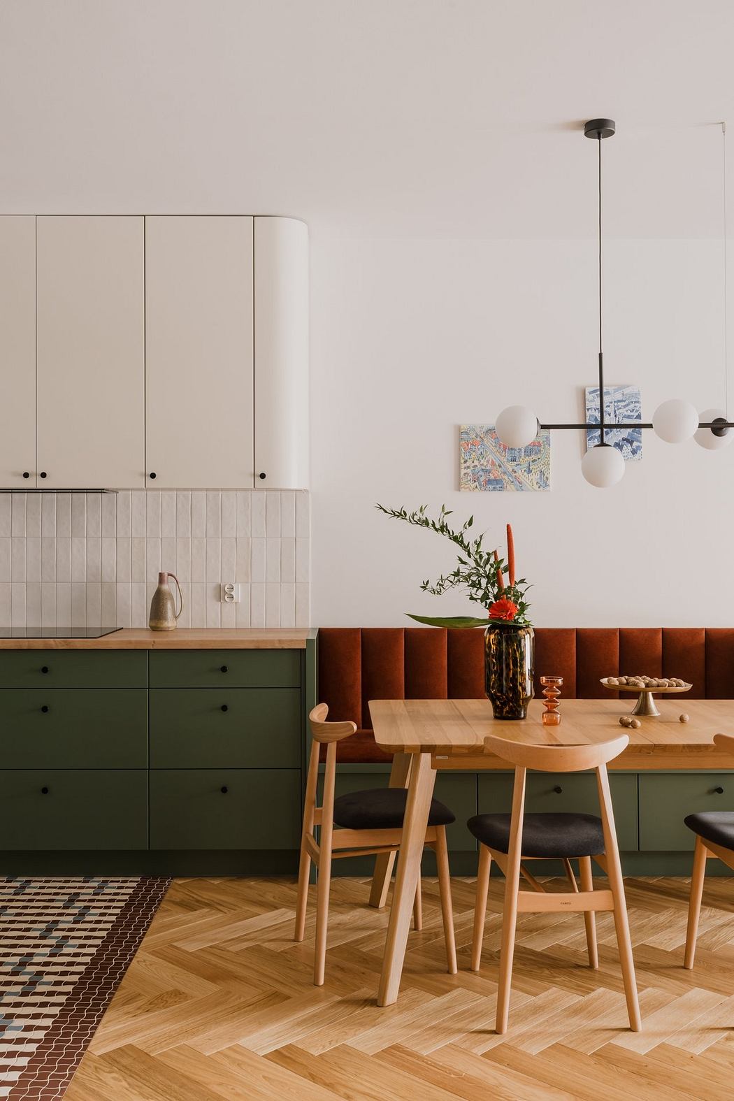 Sleek modern kitchen with green cabinets, wood table, and stylish lighting fixtures.