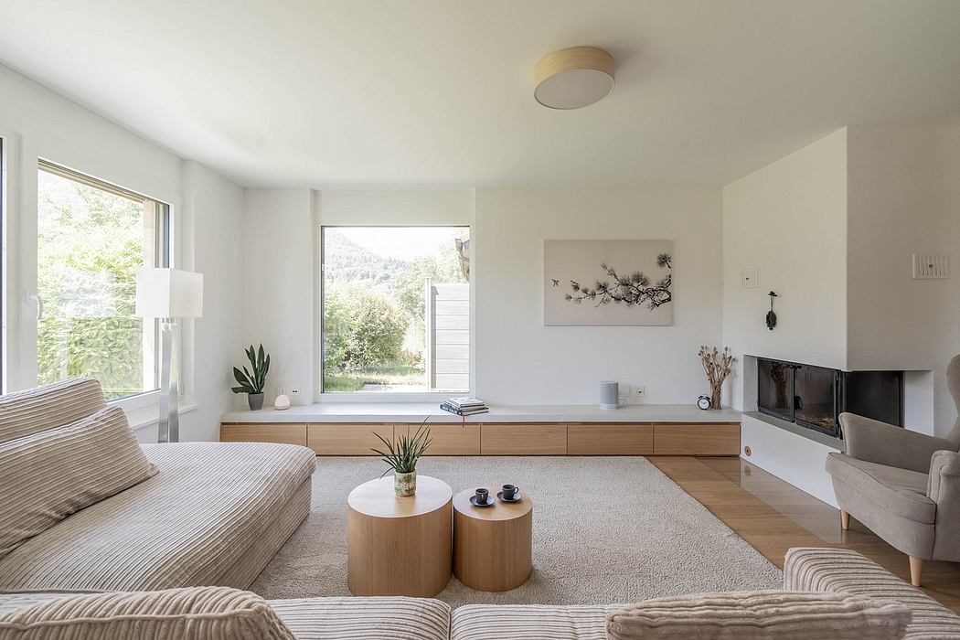 Minimalist living room with wooden accents, wall art, and large window overlooking greenery.