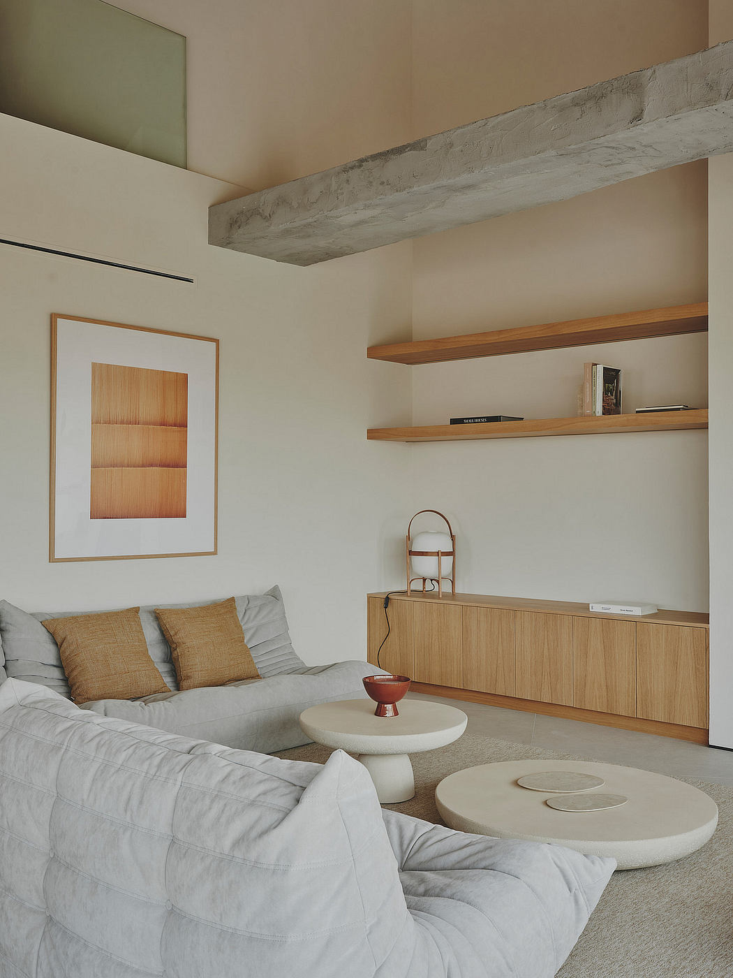 Modern living room with concrete beam, wooden shelves, and minimalist furniture.