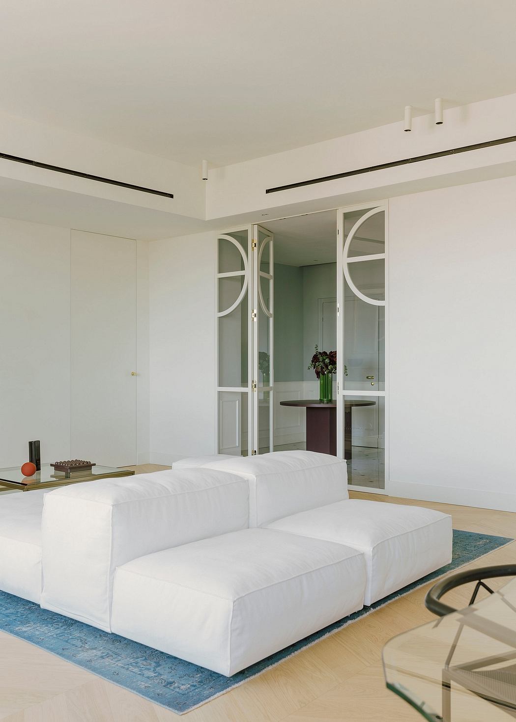 A modern, light-filled living room with arched glass doors, clean lines, and a plush white sectional sofa.