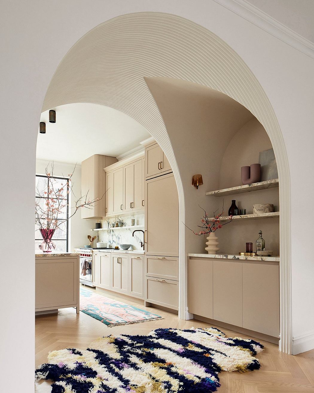 Elegant curved archway frames a cozy kitchen with warm neutral tones and stylish accents.
