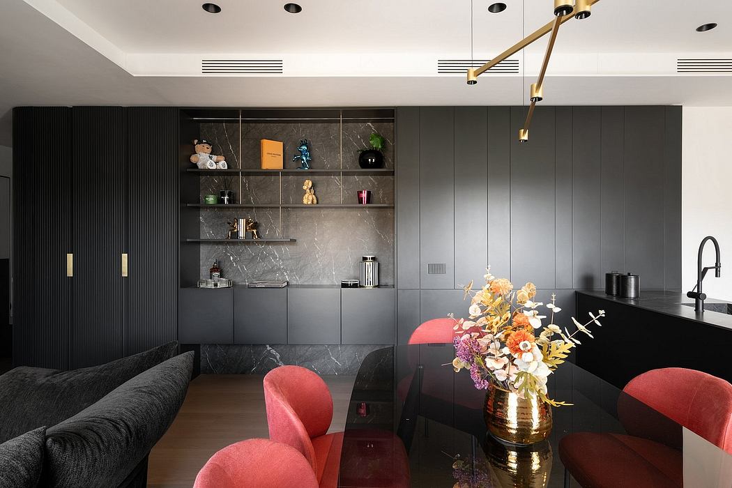 Sleek, modern kitchen with black cabinetry, colorful furnishings, and a striking chandelier.