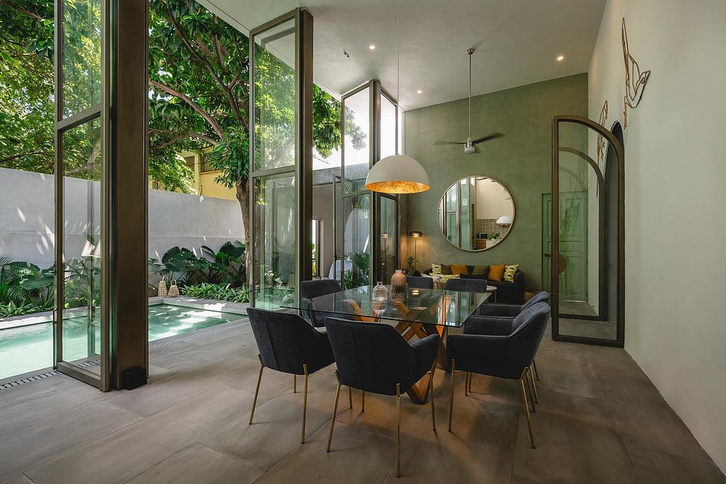 Luxurious indoor-outdoor living space with glass walls, modern furnishings, and lush greenery.