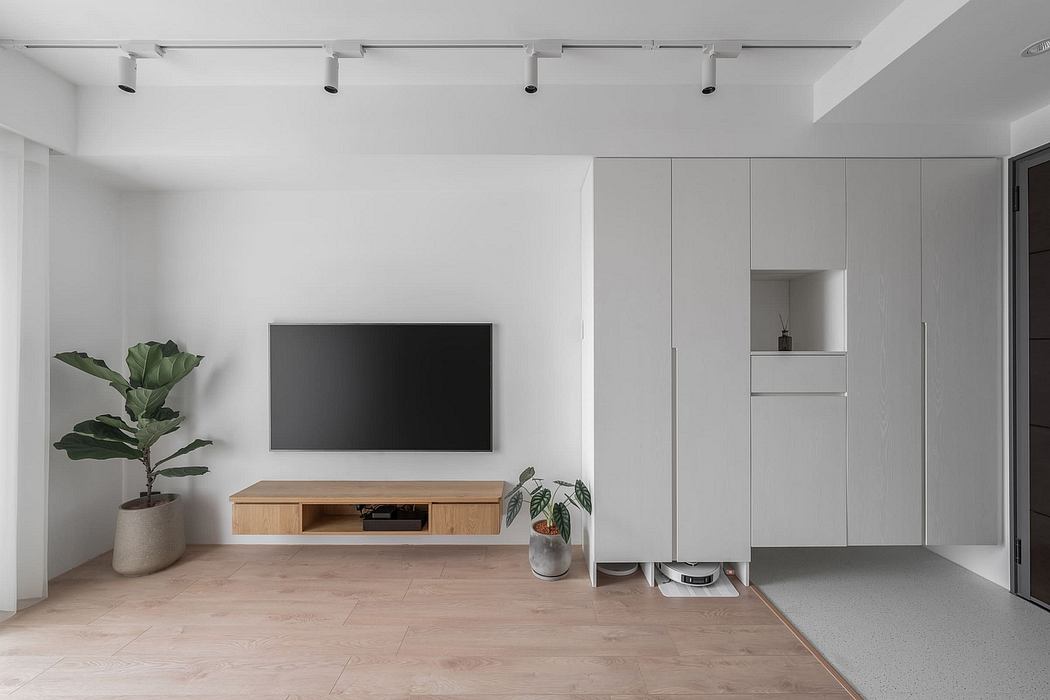 A modern, minimalist living room with a TV console, built-in cabinets, and potted plants.