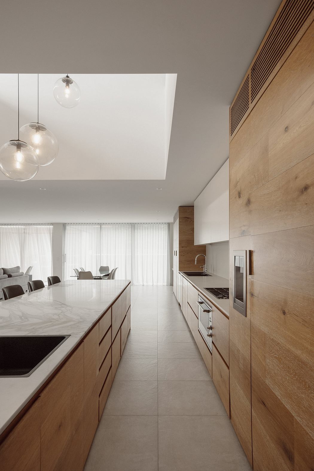 Modern open-plan kitchen with clean lines, natural wood accents, and floating light fixtures.