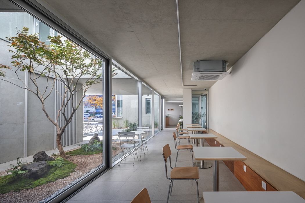 Minimalist interior with concrete ceiling, floor-to-ceiling windows, and a small courtyard garden.