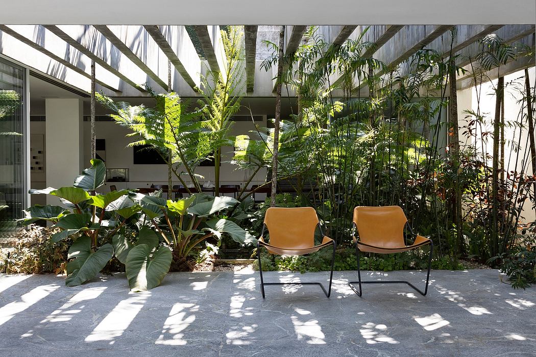 Lush tropical greenhouse interior with modern chairs, floor-to-ceiling glazing, and natural light.