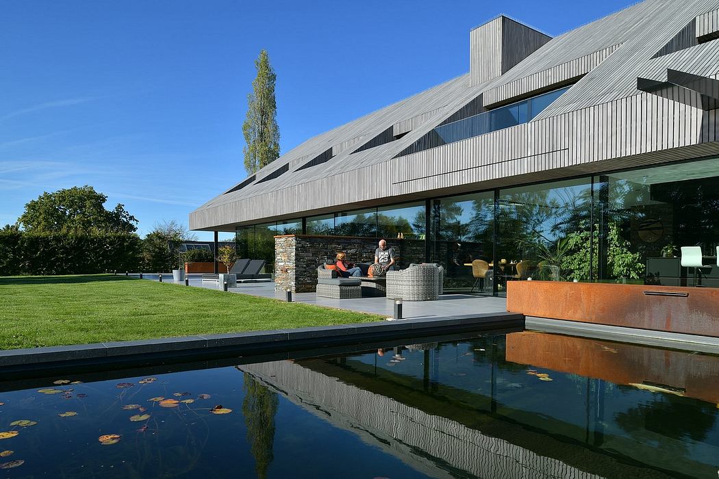 Modern architectural design with glass walls, sloped roofs, and reflecting pond.