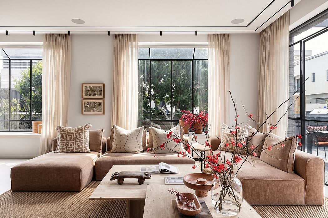 Spacious living room with large windows, plush sofas, and artful floral arrangement.