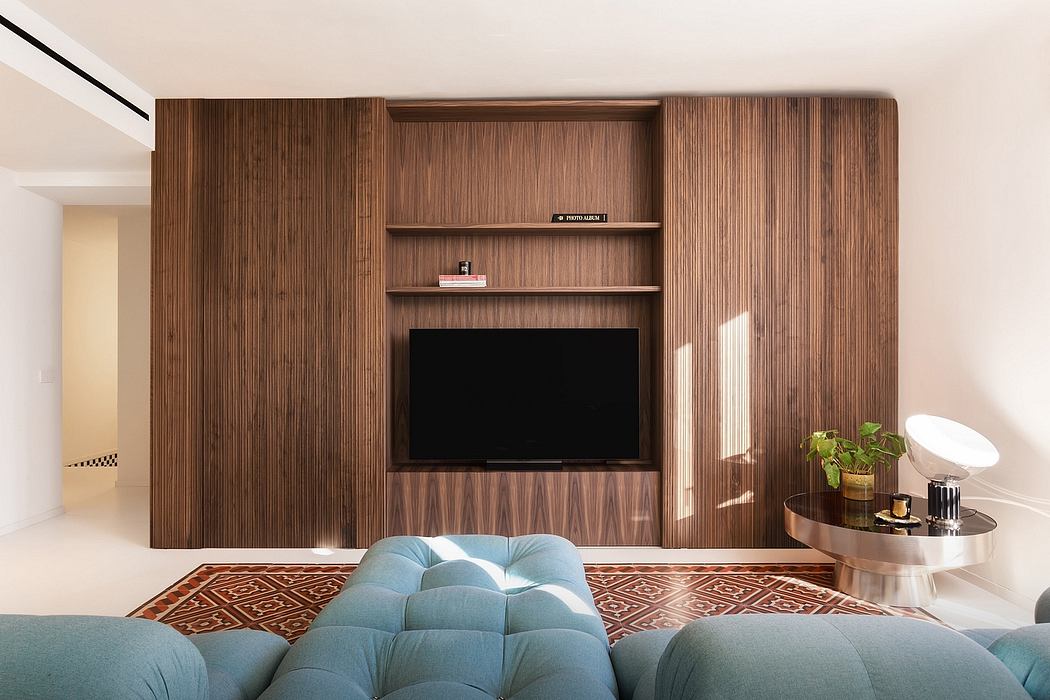 Sleek, modern living room with a large wooden TV display unit, plush blue sofa, and patterned rug.