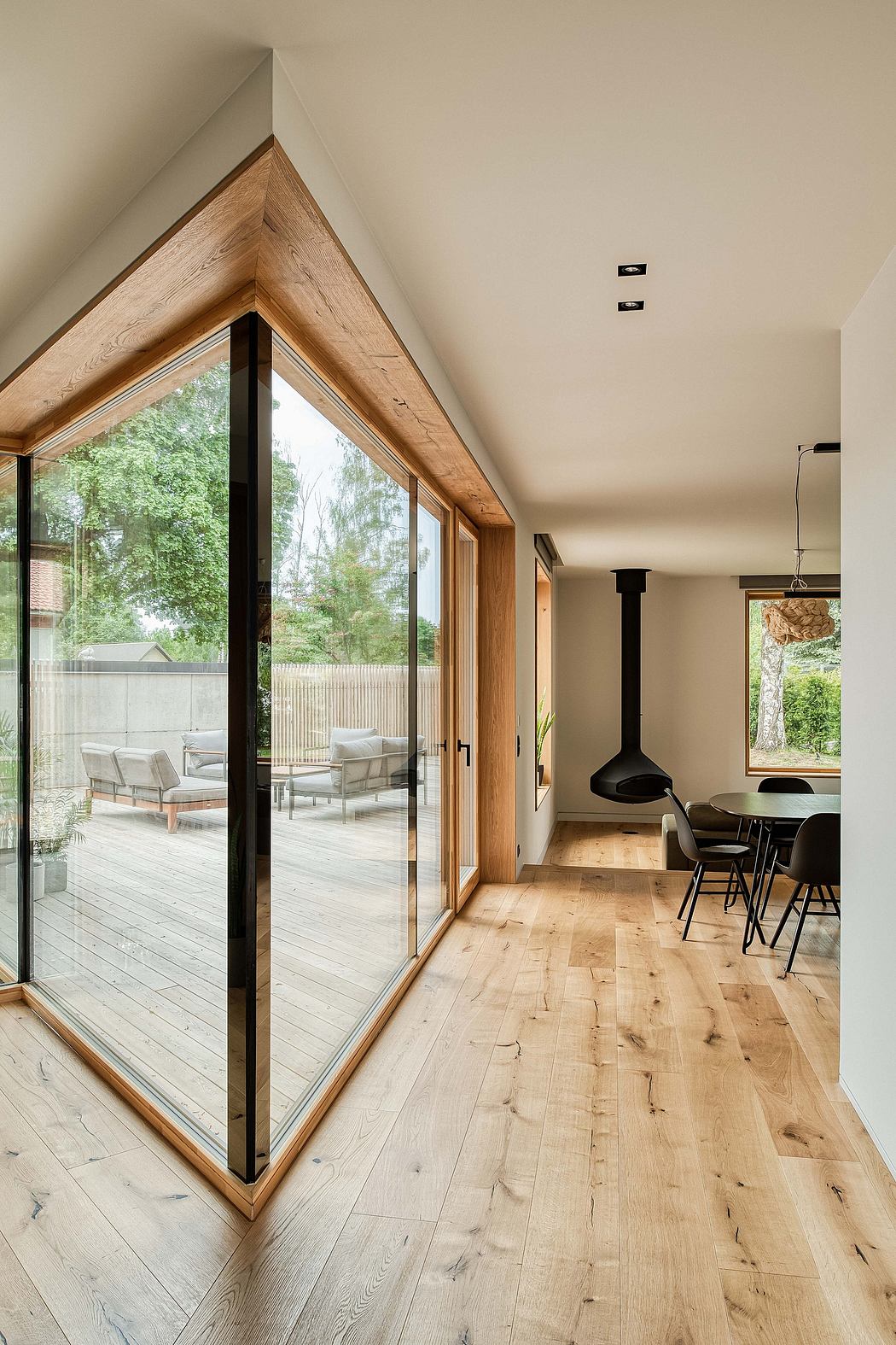 Modern, open-plan living space with large windows, natural wood accents, and a sleek fireplace.