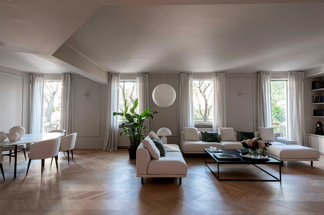 Spacious living room with large windows, light-colored furnishings, and a modern chandelier.
