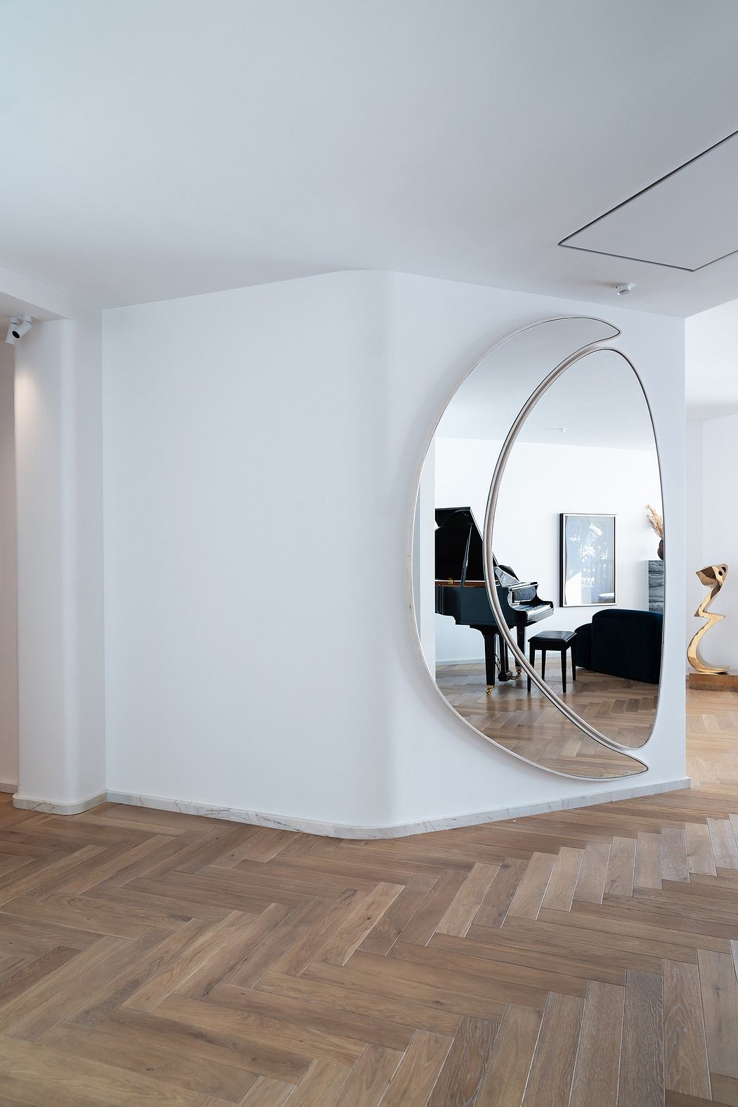 Elegant interior with curved mirror, hardwood flooring, and minimalist furnishings.