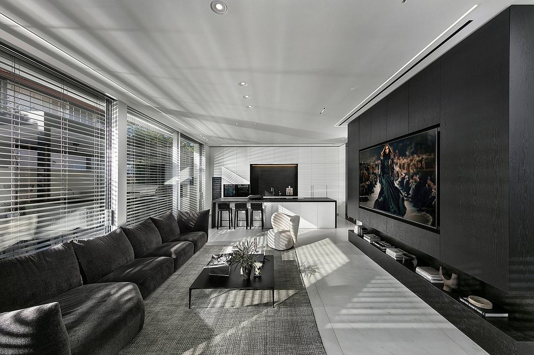 Sleek, minimalist living room with large TV, plush sofa, and modern kitchen area.