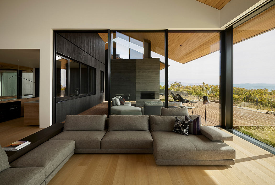 Modern and stylish living room with large windows offering scenic views, sleek furniture, and wooden accents.