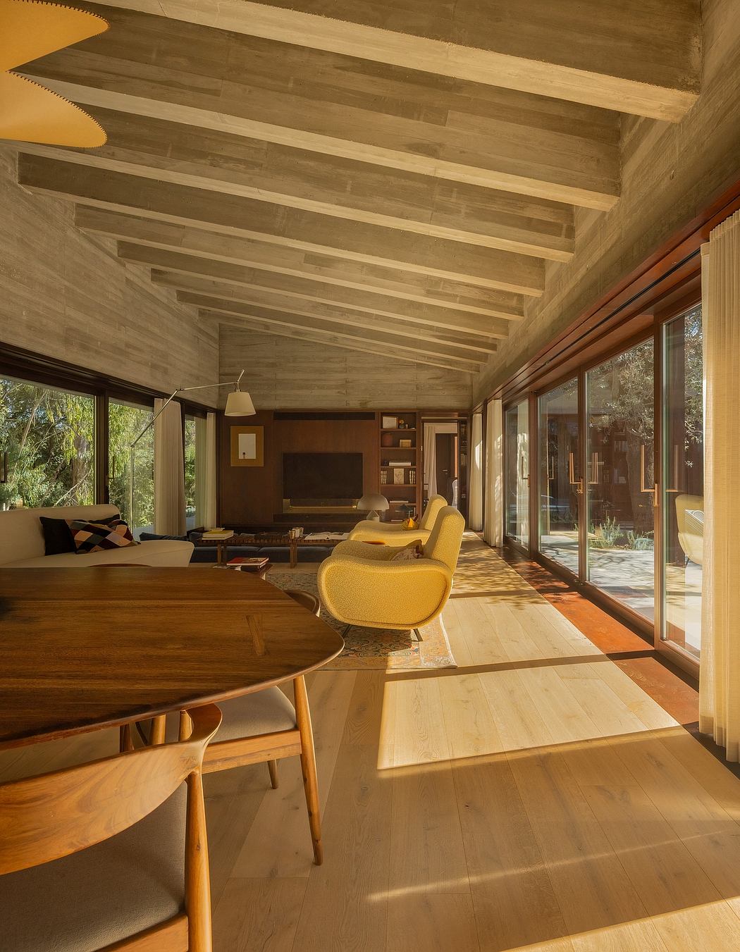 Warm-toned wooden ceiling, expansive windows, and plush yellow furniture create a cozy, modern living space.