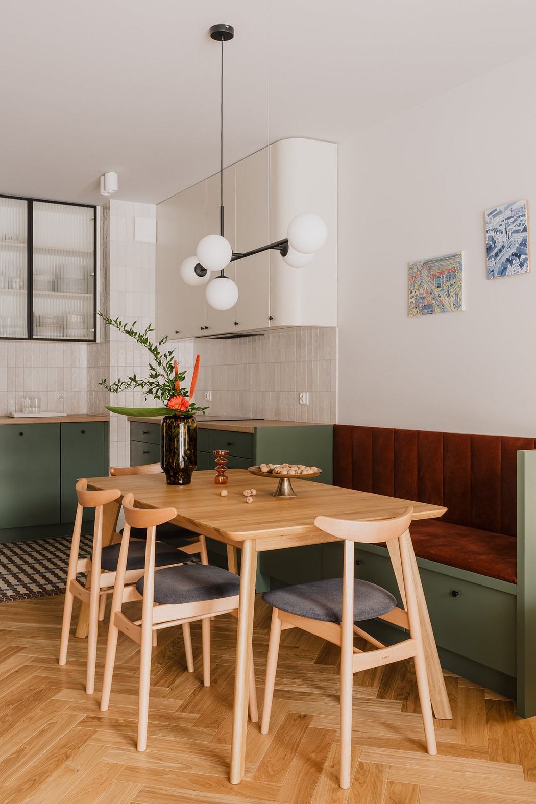 A modern kitchen with a wooden dining table, pendant lighting, and a decorative floral arrangement.