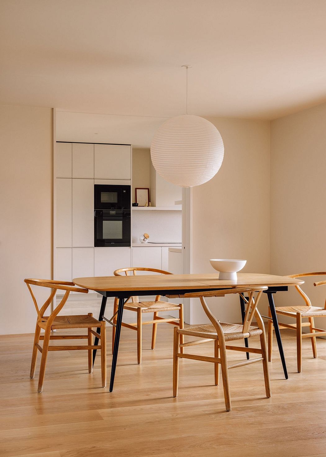 A cozy dining area with a wooden table, modern chairs, and a distinctive light fixture.
