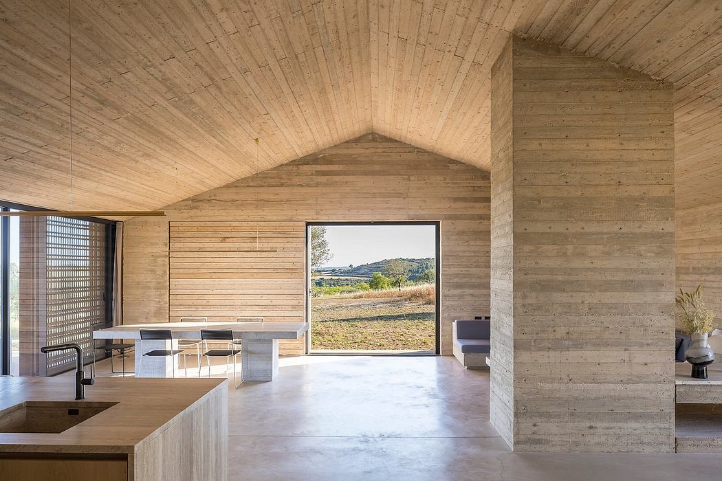 Minimalist interior with vaulted wood ceiling, concrete walls, and panoramic window view.