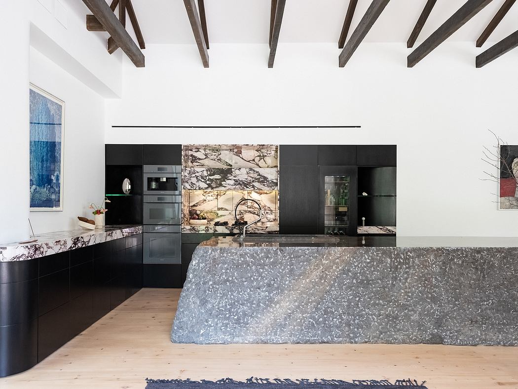 The kitchen features a stunning marble waterfall countertop, sleek black cabinetry, and exposed wooden beams.