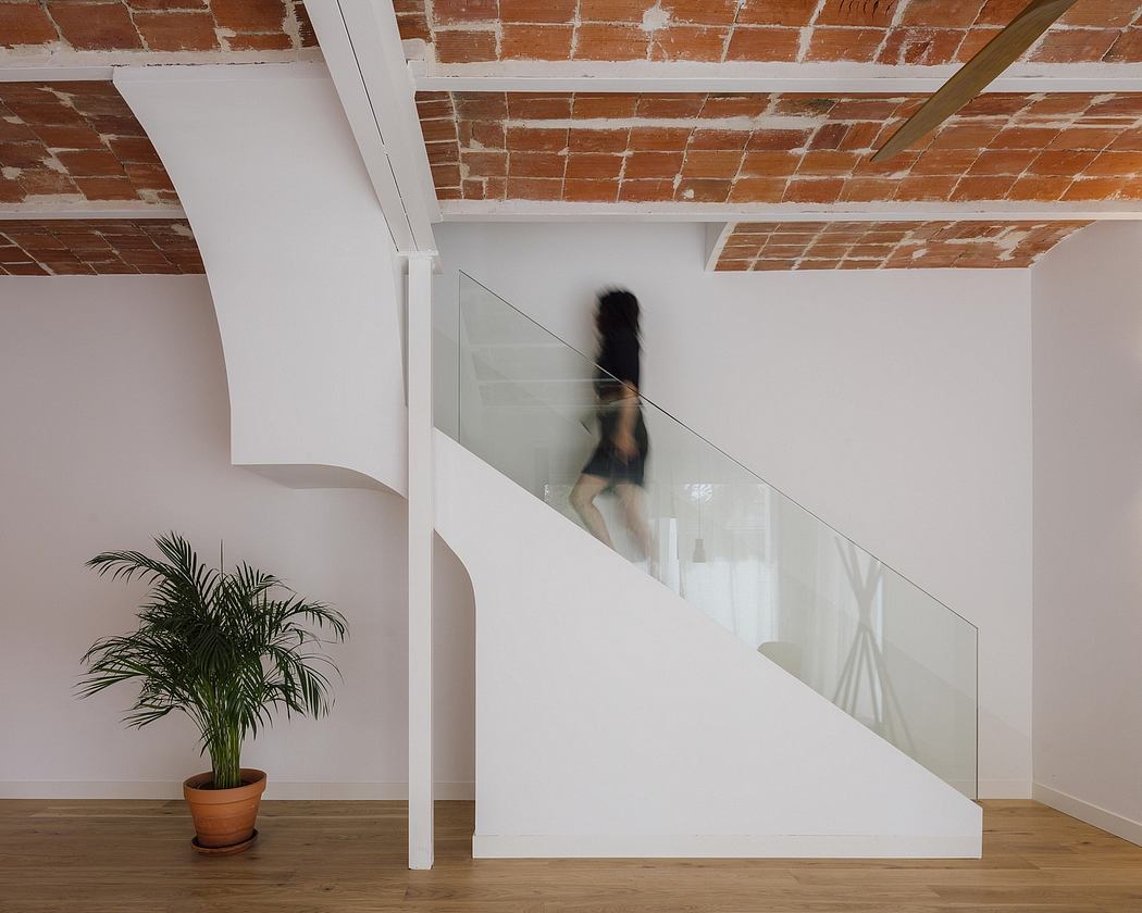 Minimalist interior with exposed brick ceiling, glass divider, and potted plant.