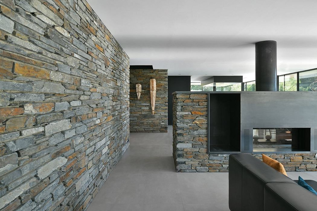 A striking interior with stone walls, sleek black furnishings, and a modern fireplace.