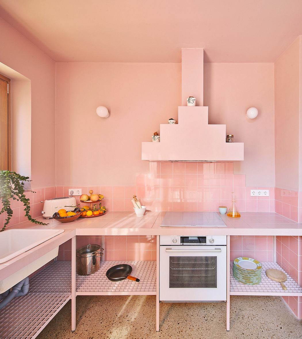 A bright, whimsical kitchen with pink tiled walls, floating shelves, and sleek appliances.