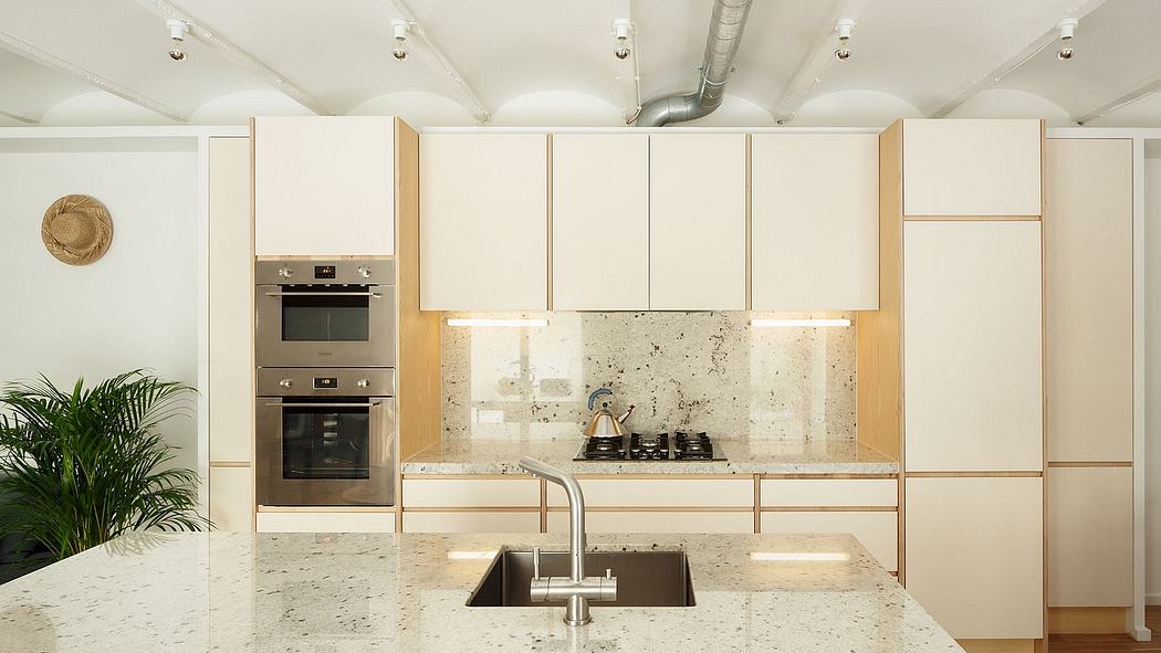 Sleek, modern kitchen with light-colored cabinetry, stone countertops, and built-in appliances.