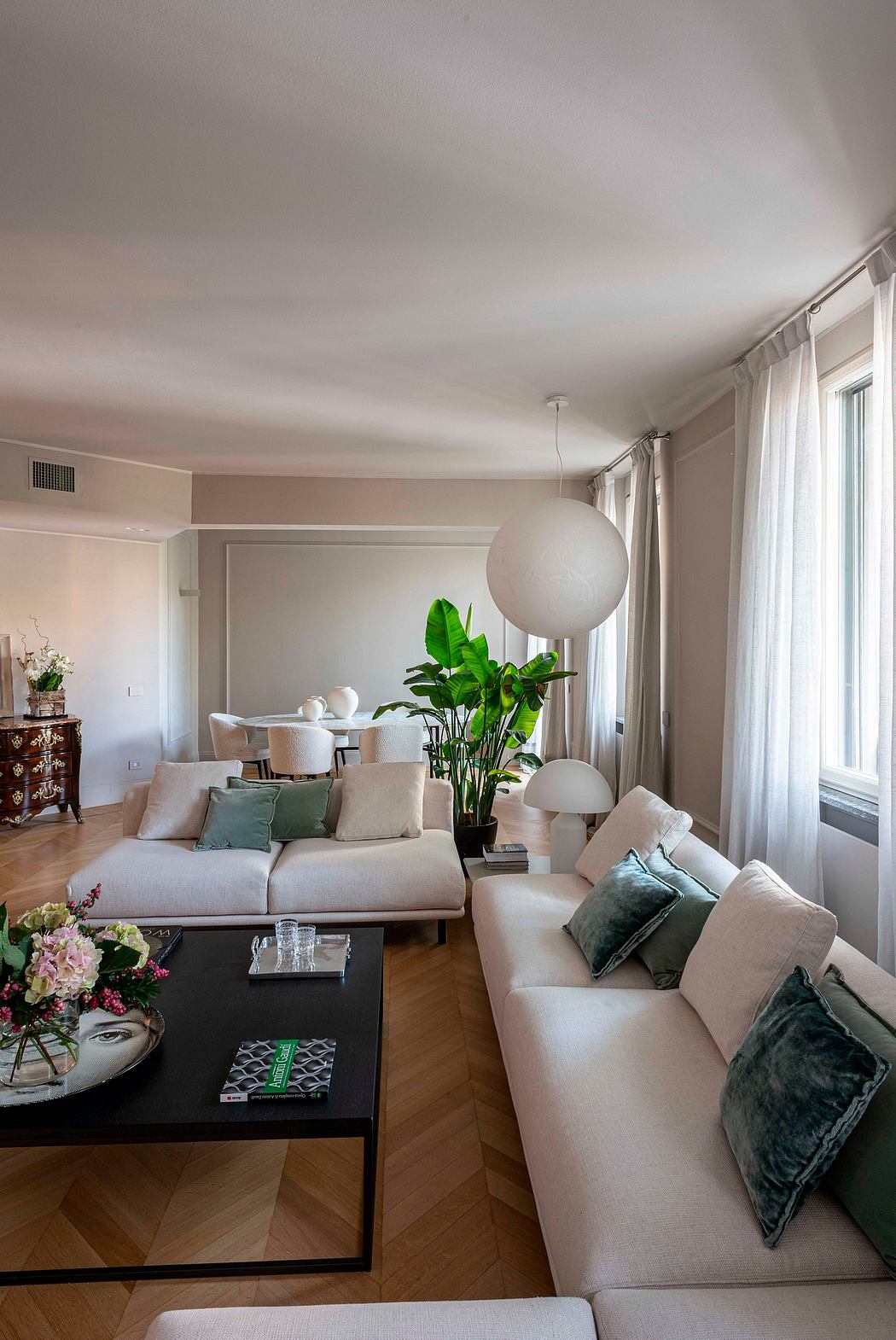 Spacious living room with neutral-toned furniture, lush potted plant, and pendant lighting.