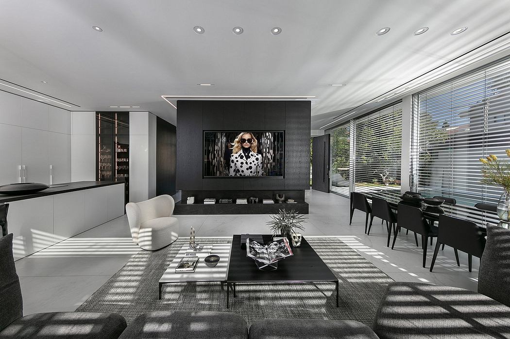 Luxurious open-concept living room with sleek black and white decor, large TV, and natural light.