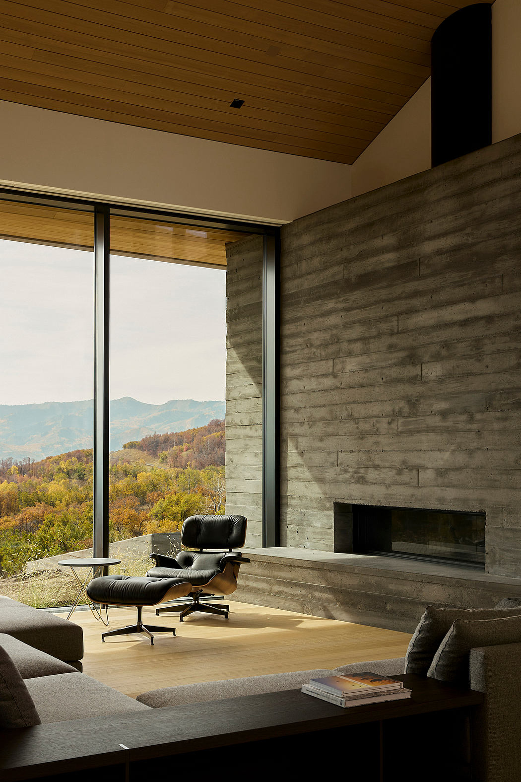 Rustic interior with large windows showcasing vibrant autumn landscape.