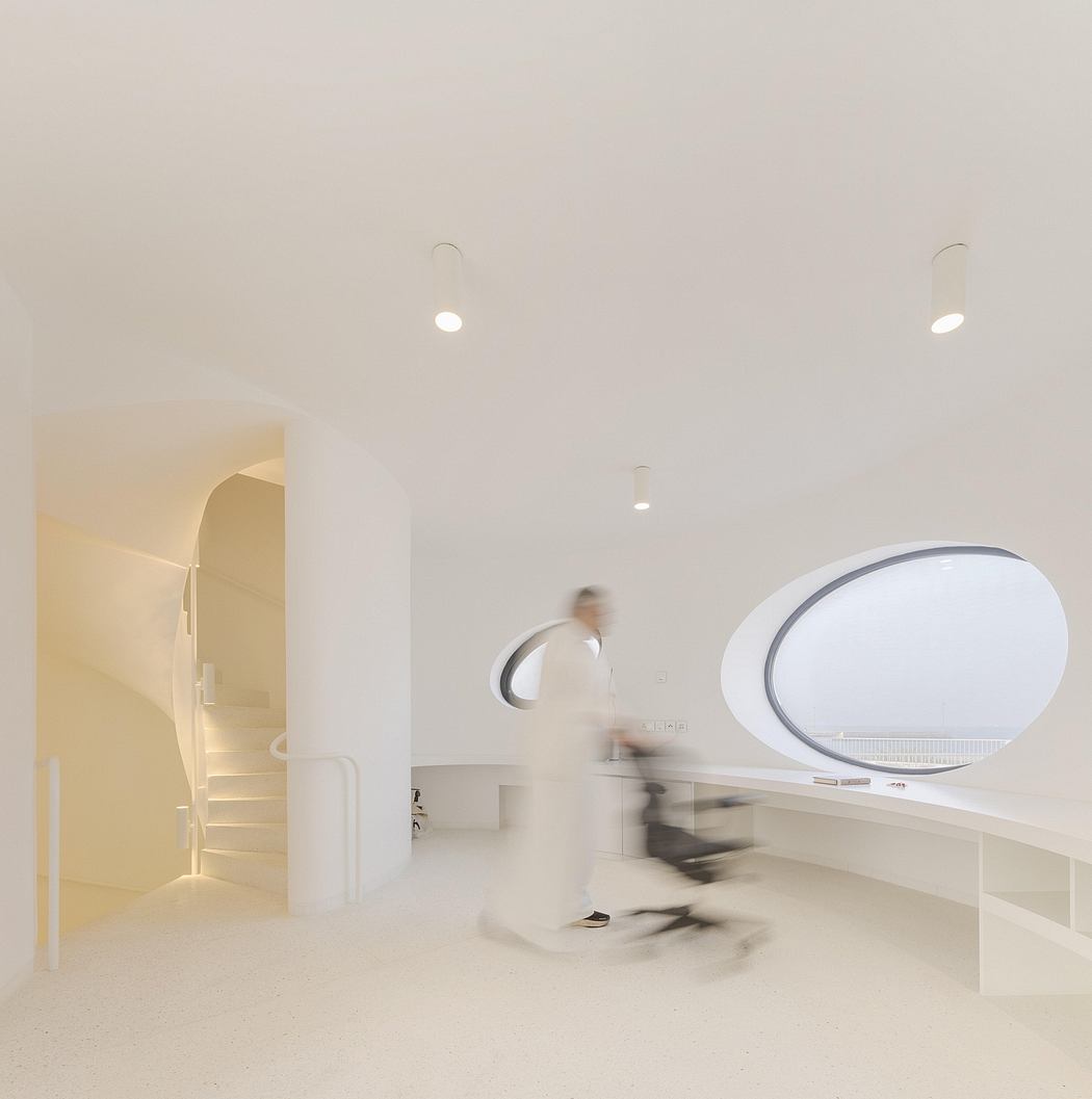 Minimalist interior with curved wall, circular light fixture, and blurred figure in motion.