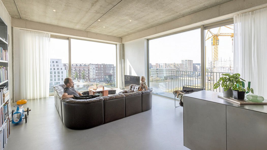 Spacious modern apartment with large windows, concrete ceiling, and comfortable seating.